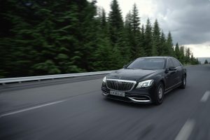 Black luxury sedan driving on an open road through a forest in Tashkent Region, Uzbekistan. Berline de luxe noire conduisant sur une route ouverte à travers une forêt dans la région de Tachkent, en Ouzbékistan.