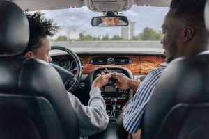 Father and teenage son inside car learning to drive, fostering bonding and guidance. Un père et son fils adolescent à l'intérieur d'une voiture apprenant à conduire, favorisant les liens et les conseils.