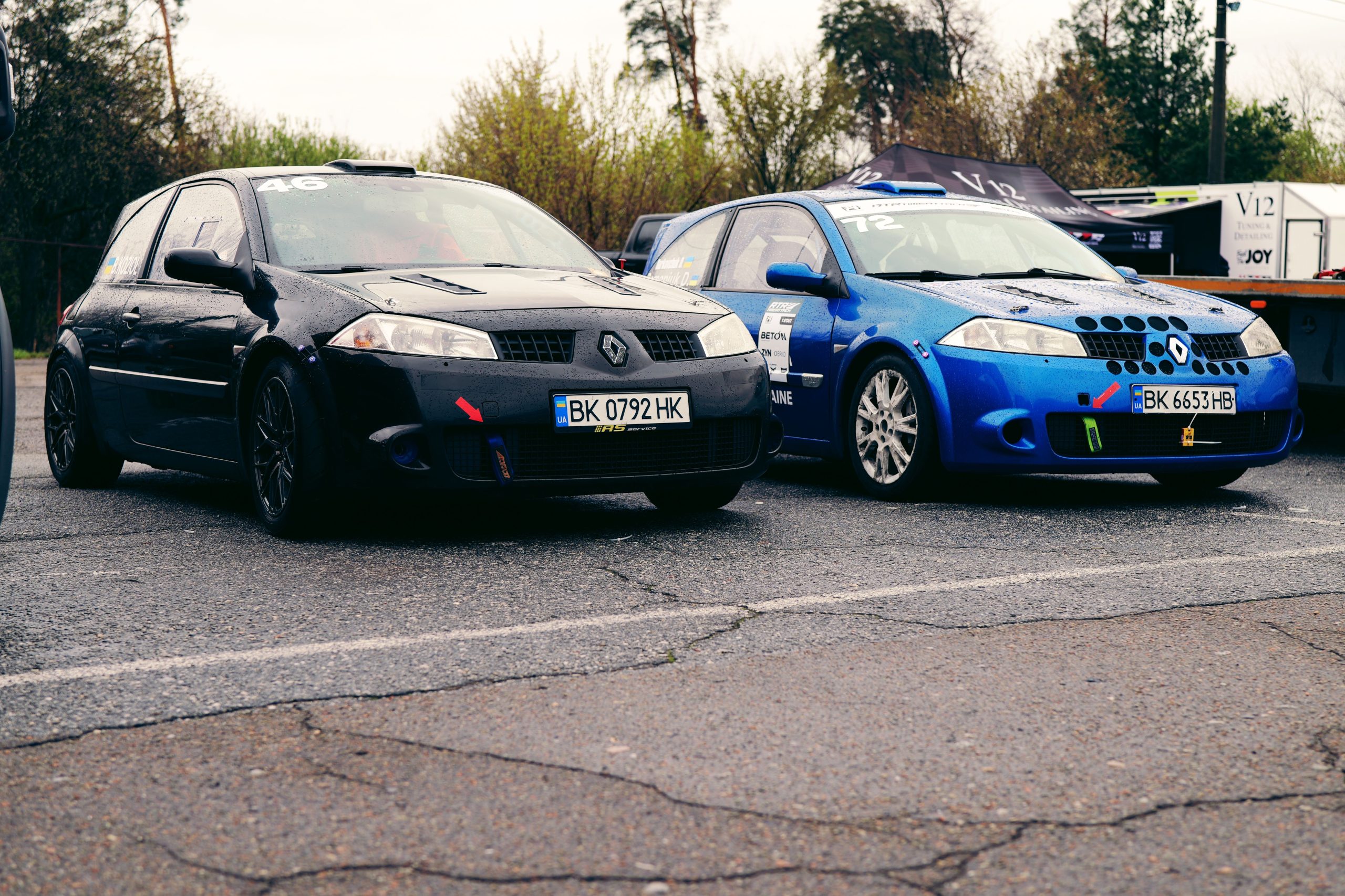 Two Renault racing cars parked at an outdoor event in Ukraine, showcasing dynamic designs. Deux voitures de course Renault garées lors d'un événement en plein air en Ukraine, mettant en avant des designs dynamiques.