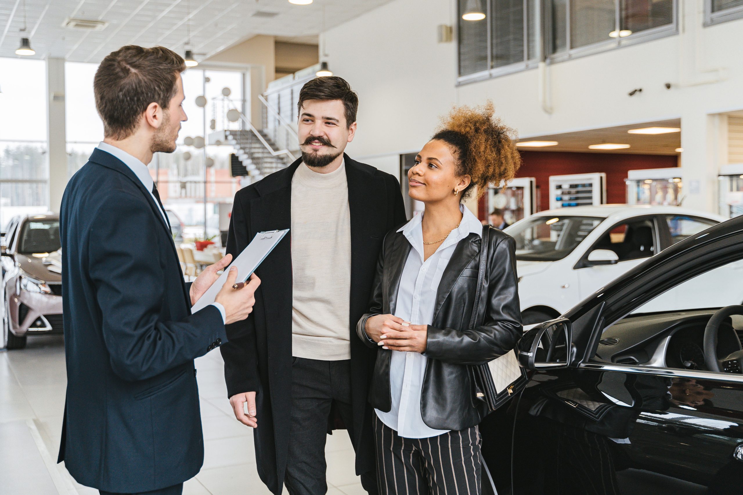 Couple et vendeur discutent achat voiture