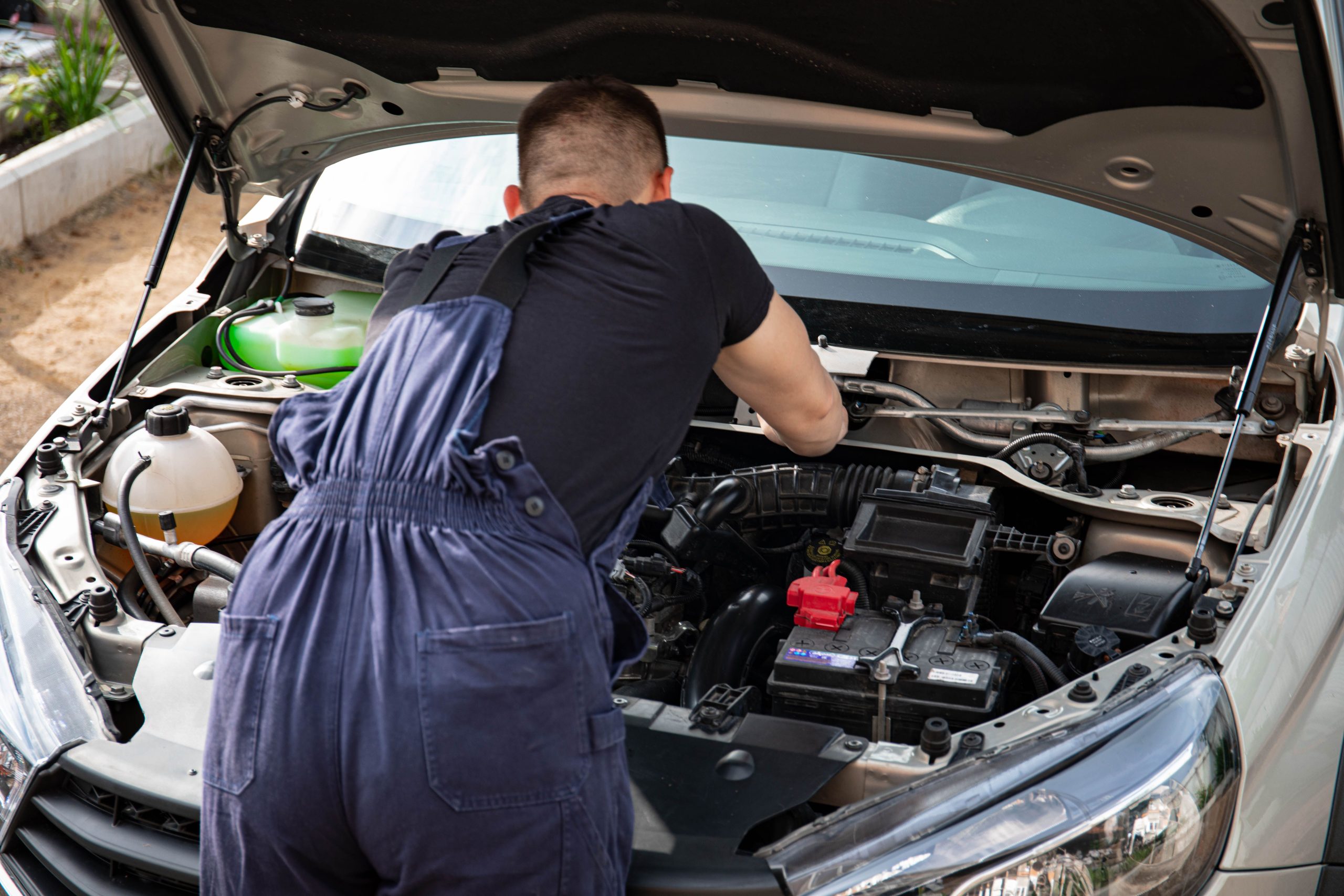 Mécanicien effectuant maintenance moteur voiture en extérieur