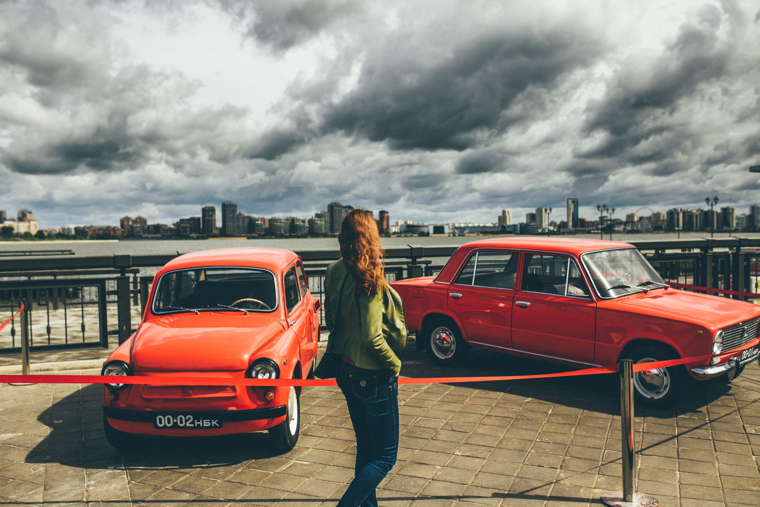 Femme observe voitures rouges classiques exposition auto