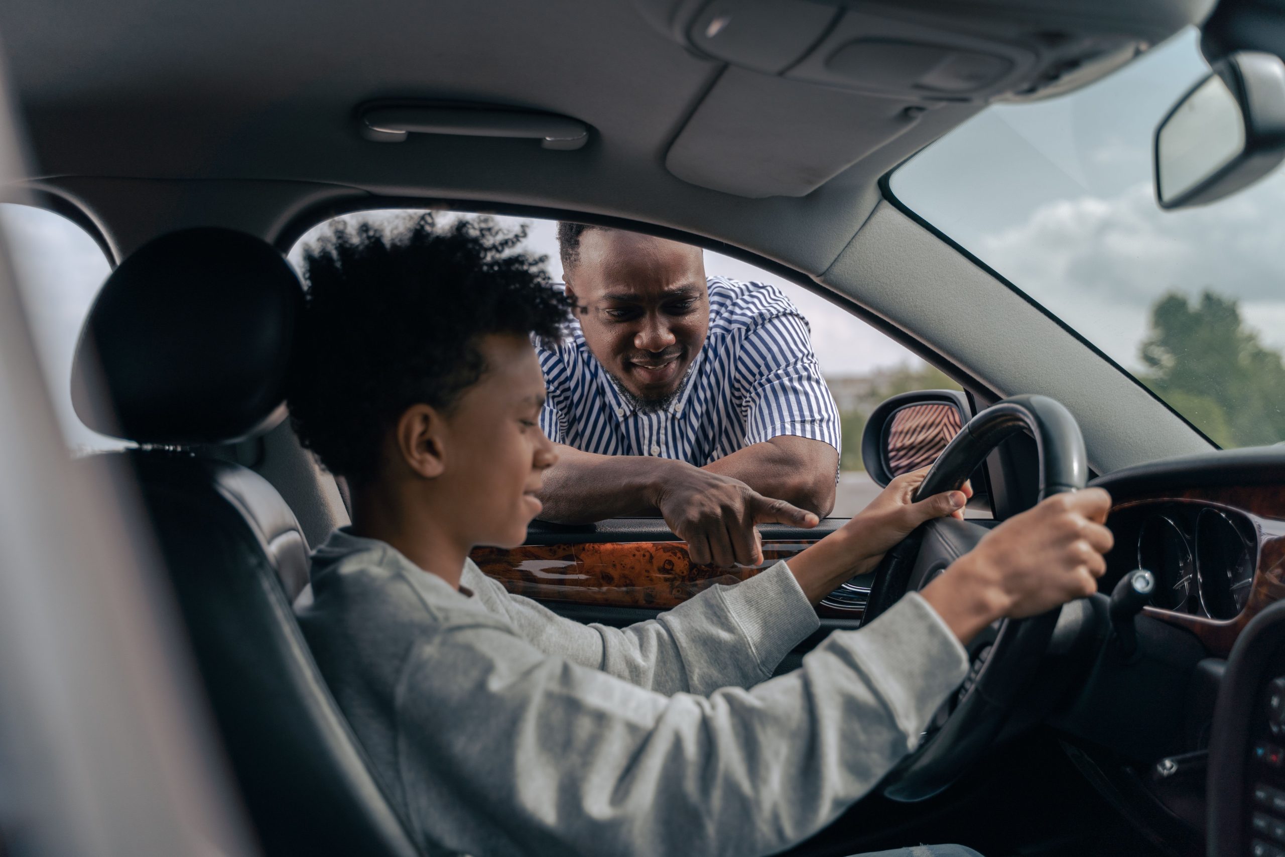 Jeune garçon au volant avec père instructeur dehors