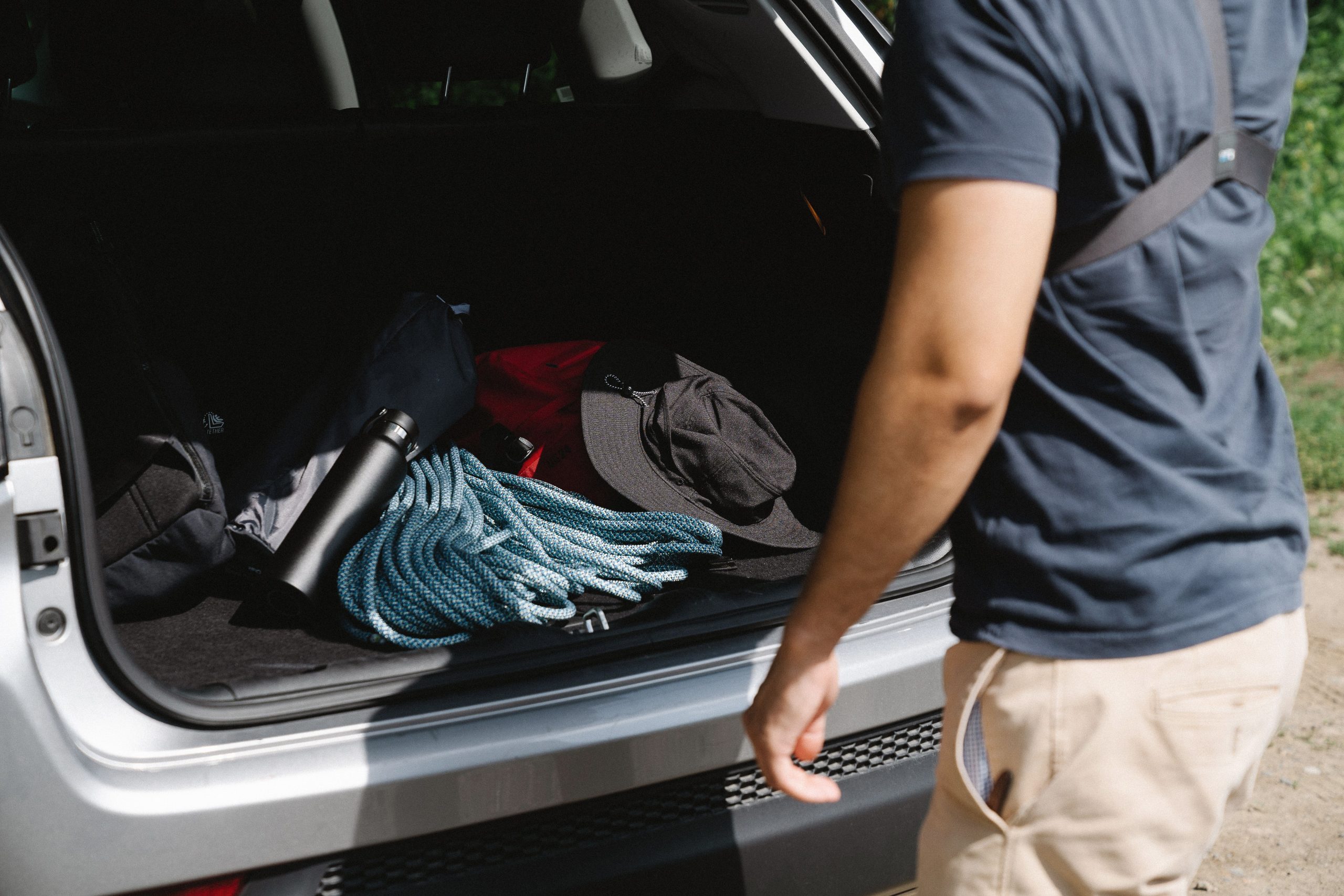 Homme organisant équipement camping dans coffre voiture